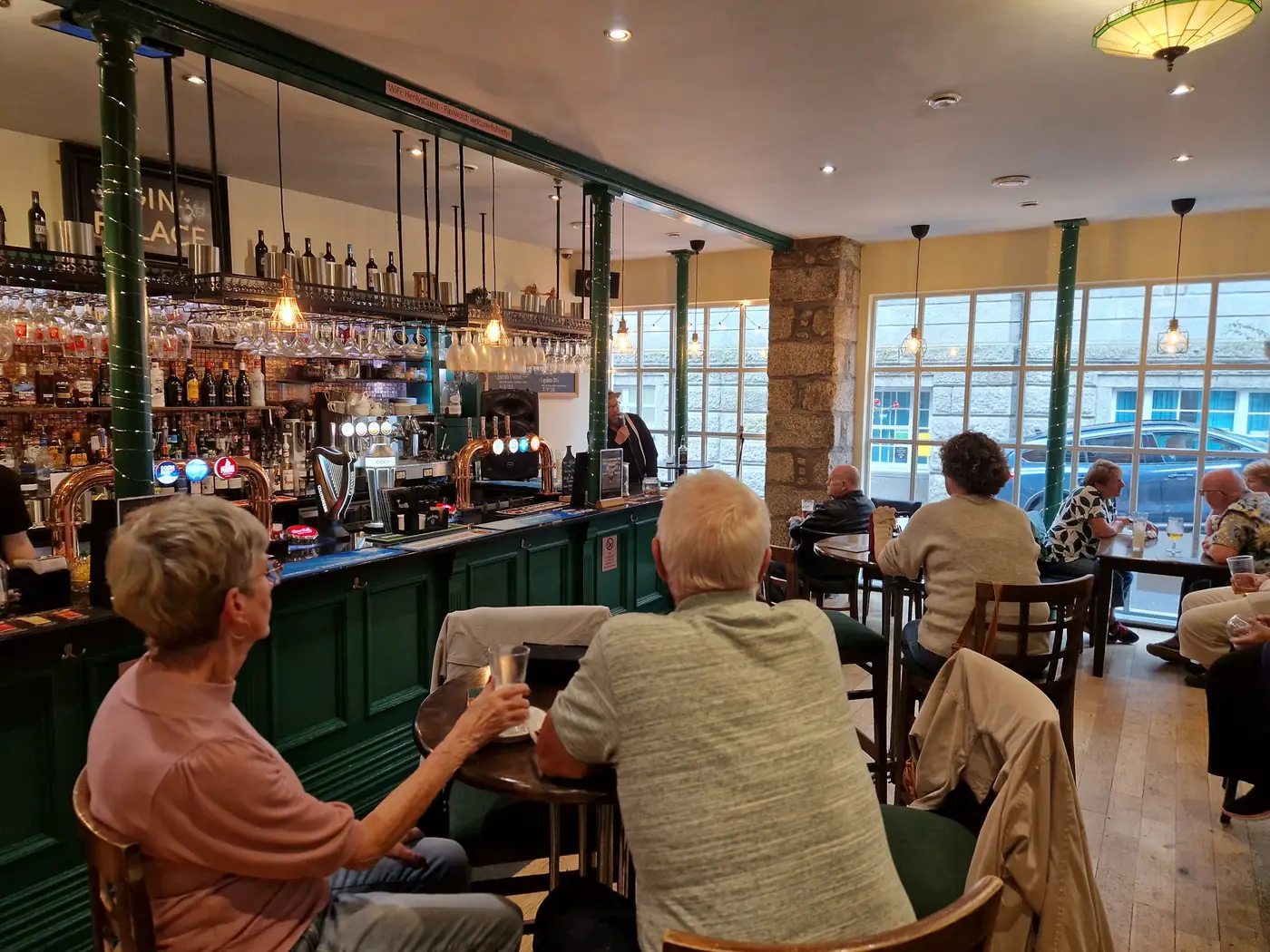 The bar at Henlys: green panelling, copper taps, hanging glassware and tall windows onto the street.